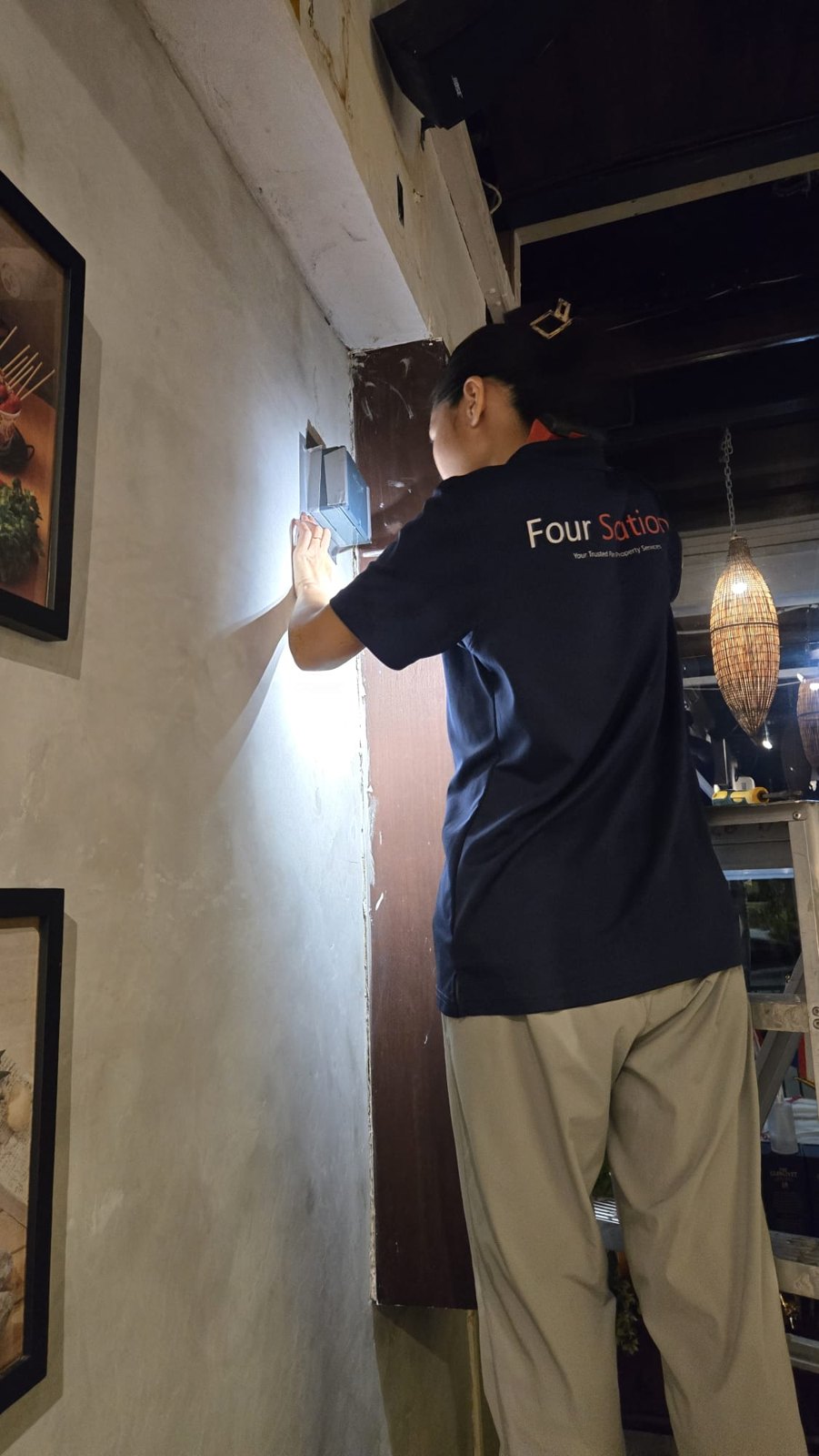 A Four Solutions technician inspecting an indoor wall junction